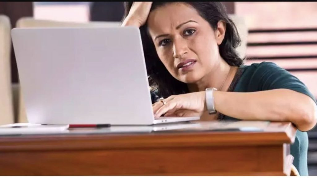 A woman in front of a laptop wearing a distressed expression
