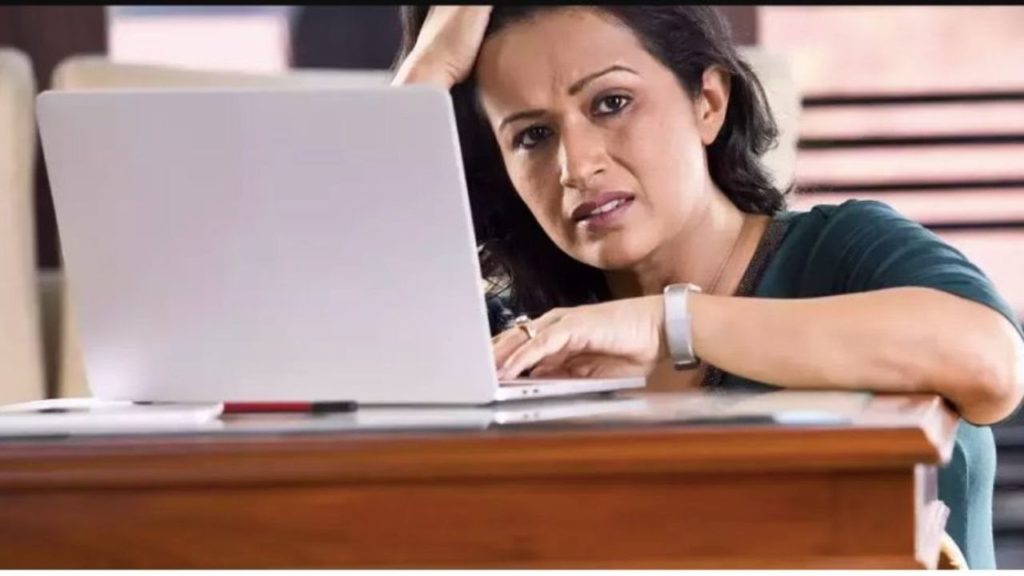 A woman in front of a laptop with a distressed facial expression
