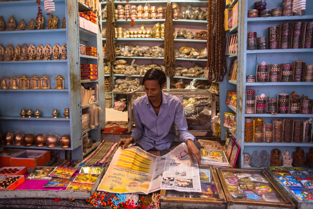 A souvenir seller reading a newspaper inside his shop