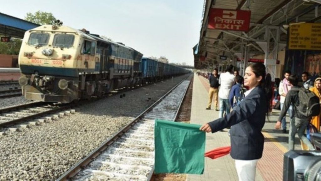 A person waving a green flag as a train arrives at a station