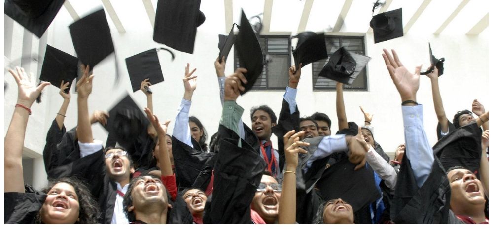 Students at a graduation ceremony throw their caps in the year