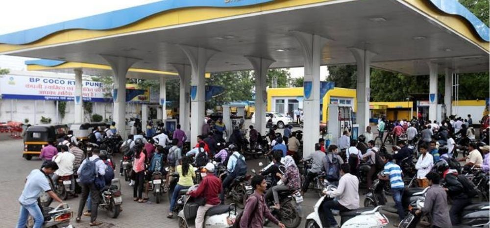People on two-wheelers lined up at a fuel station