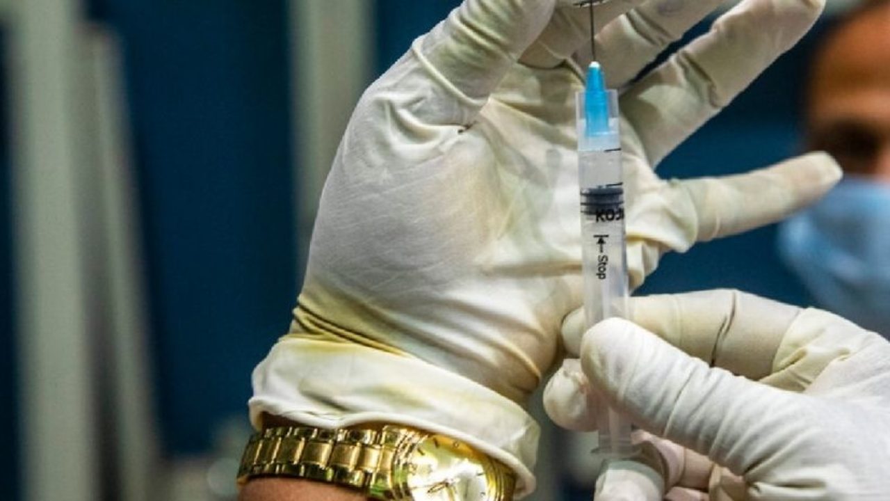 Close up of a health worker's hand holding a syringe
